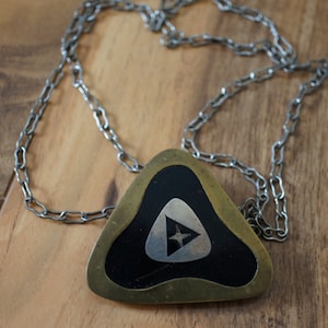 May include: A silver chain necklace with a triangular pendant. The pendant is made of brass and has a black enamel inlay with a silver star design.