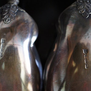 May include: Two silver pear-shaped serving spoons with ornate handles and hallmarks on the back.