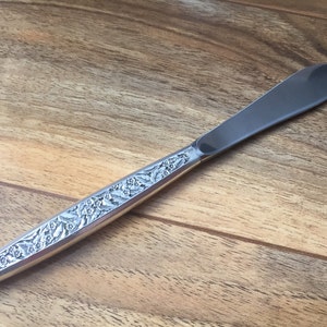 Könnte beinhalten: Ein silbernes Buttermesser mit einem floralen Muster auf dem Griff.