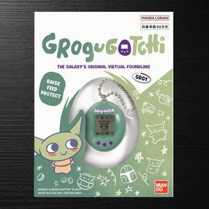 May include: A Grogugotchi virtual pet device in a green plastic shell with a metal chain, packaged in a white and green box featuring the text Grogugotchi, The Galaxy's Original Virtual Foundling, Raise Feed Protect, and various line art illustrations.