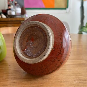 A handmade, red-brown ceramic vase with a glossy finish.