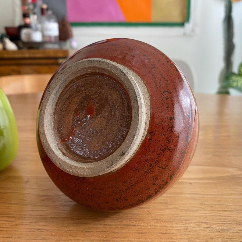 A handmade, red-brown ceramic vase with a glossy finish.