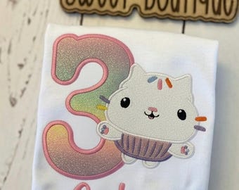 Koszulka urodzinowa z babeczką i kotem • Spersonalizowana koszulka urodzinowa dla dziewcząt • Urodzinowy strój kotka • Haftowana koszulka z kotem • Uroczy top urodzinowy z babeczką