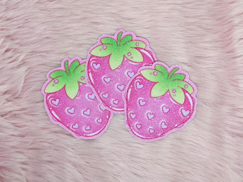 May include: Three pink glitter strawberry patches with green leaves and white hearts.
