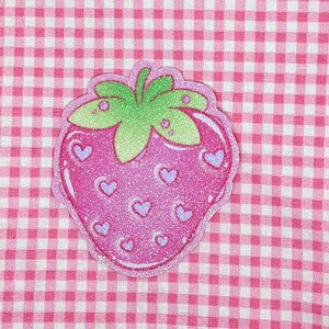 May include: A pink and green glitter strawberry with a white background. The strawberry has a green stem and leaves and is covered in small pink hearts.