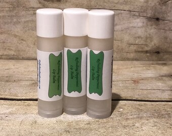 May include: Three white tubes of lip balm with green labels that say "Refreshing Peppermint Lip Balm".