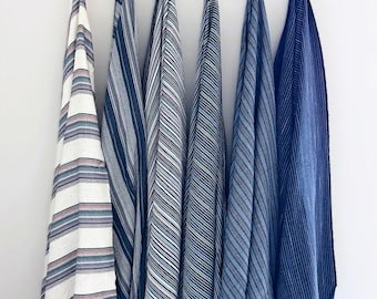 May include: Five striped towels hanging on a wooden rack. The towels are in shades of blue and white.
