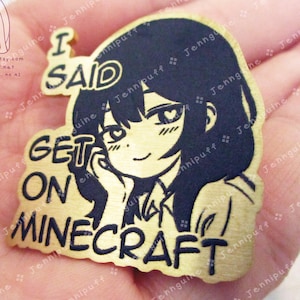 May include: A gold-colored metal pin featuring a black anime-style illustration of a girl with the text "I SAID GET ON MINECRAFT". The pin has a rectangular shape with rounded edges, suitable for attaching to clothing or bags.