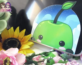 May include: A green apple with a cute cartoon face and a leaf on top. The apple is on a blue background with white clouds and stars. The image is a sticker.