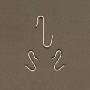 May include: Three small, silver-colored metal hooks are arranged against a solid brown background. One hook is a simple, upside-down "J" shape, while the other two are more curved, resembling the number "2" and the letter "S".