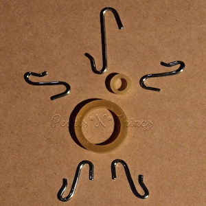 May include: A set of eight silver-colored metal hooks arranged in a starburst pattern around a pair of gold-colored metal rings. The rings are different sizes and are placed on a brown surface. The text "Pearls & Things" is visible in the lower center of the image.