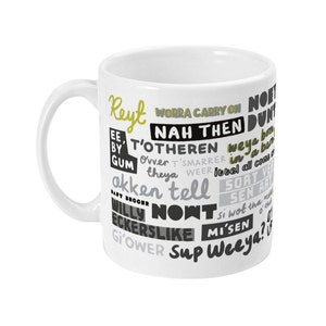 Può includere: Tazza in ceramica bianca con manico, ricoperta da un collage di frasi in vari font e colori, tra cui nero, grigio e giallo. Le frasi sono disposte a cerchio attorno alla tazza.