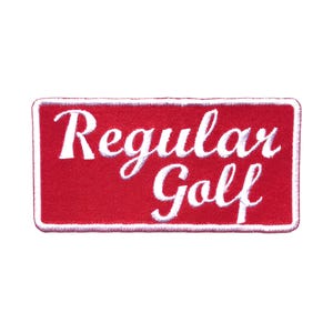 May include: A rectangular red patch with white embroidered text that reads "Regular Golf". The patch has a white border and is set against a white background. The text is in a cursive font.