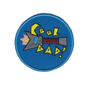 May include: A blue circular patch with a cartoon image of a rocket ship with the text "Cool Dad!" in yellow letters.