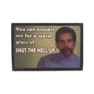 May include: A black and green embroidered patch with a man's face and the text "You can trouble me for a warm glass of SHUT THE HELL UP".