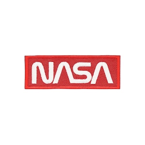 Pu&ograve; includere: Una toppa rettangolare con il logo NASA. La toppa ha uno sfondo rosso con il testo NASA bianco in grassetto, in un carattere sans-serif. &Egrave; destinata all'applicazione su abbigliamento o accessori.