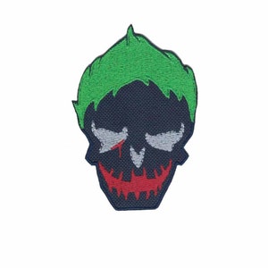 May include: Green and black embroidered patch of a skull with a red smile and a white scar. The skull has a green mohawk.