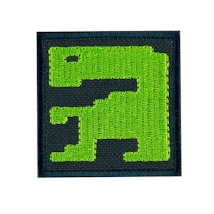 May include: Green pixelated dinosaur embroidered on a dark gray square patch.