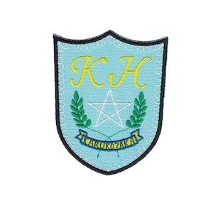 May include: Embroidered patch in a shield shape with a light blue background. Features yellow initials "KH", a white star, green sprigs, and the text "KARUKOZAKAI" on a blue banner. The patch is outlined in black.