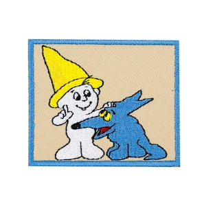 May include: An embroidered patch featuring a white character with a yellow hat and a blue dog. The character is smiling and holding the dog's paw. The patch is surrounded by a blue border.