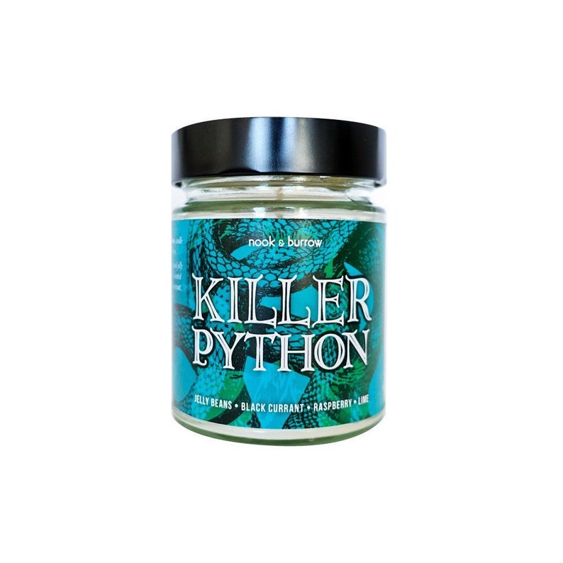 Puede incluir: Una vela de vidrio en un frasco con tapa negra y una etiqueta verde y blanca que dice "nook & burrow" y "Killer Python" con el texto "Jelly Beans, Black Currant, Raspberry, Lime" debajo.