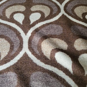 May include: A brown, beige, and white patterned throw blanket with a soft, textured surface.