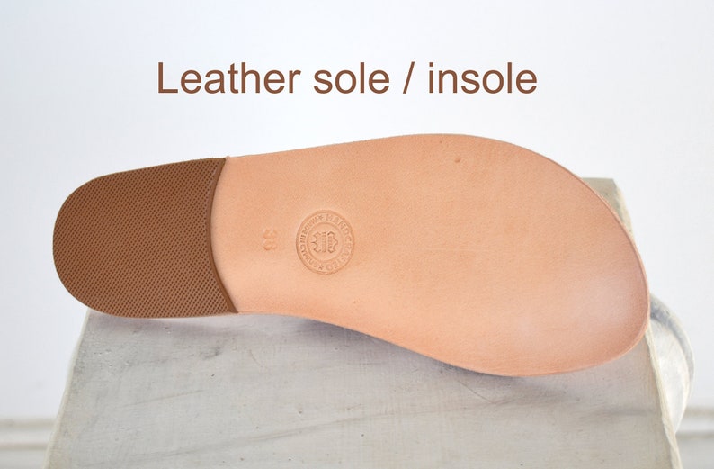 May include: A close-up of a leather shoe sole and insole. The sole is a light brown color with a textured heel. The insole is a lighter shade of brown with a circular stamp and the number 38. The text "Leather sole / insole" is at the top.
