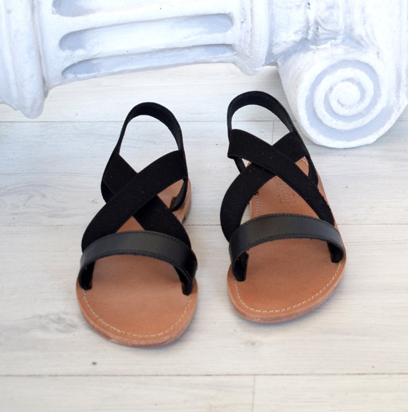 May include: Black leather sandals with criss-cross straps and a brown sole.