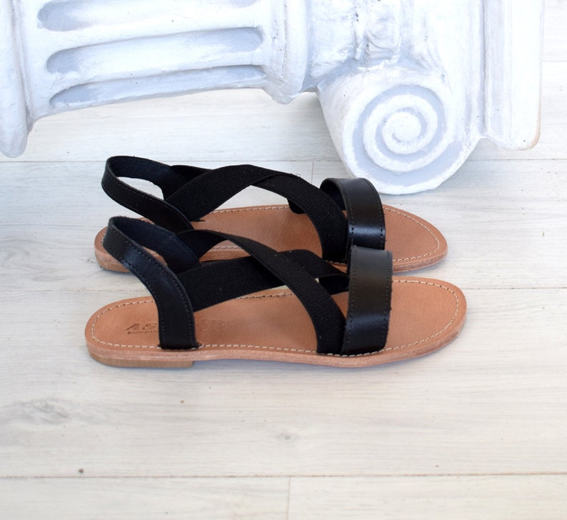 May include: Black leather sandals with criss-cross straps and a brown leather sole.
