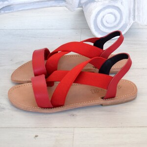 May include: Red leather sandals with criss-cross straps and a brown leather sole.