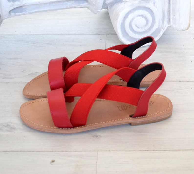 May include: Red leather sandals with criss-cross straps and a brown leather sole.