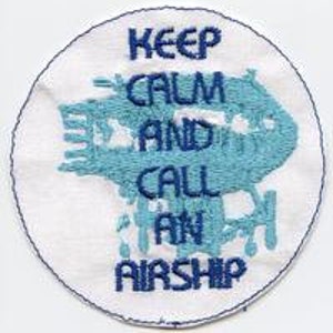 May include: White round embroidered patch with blue text that reads "Keep Calm and Call an Airship".