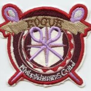 May include: A red, white and purple embroidered patch with the word "ROGUE" in a banner above a pair of scissors and the words "Embroiderers Guild" below.