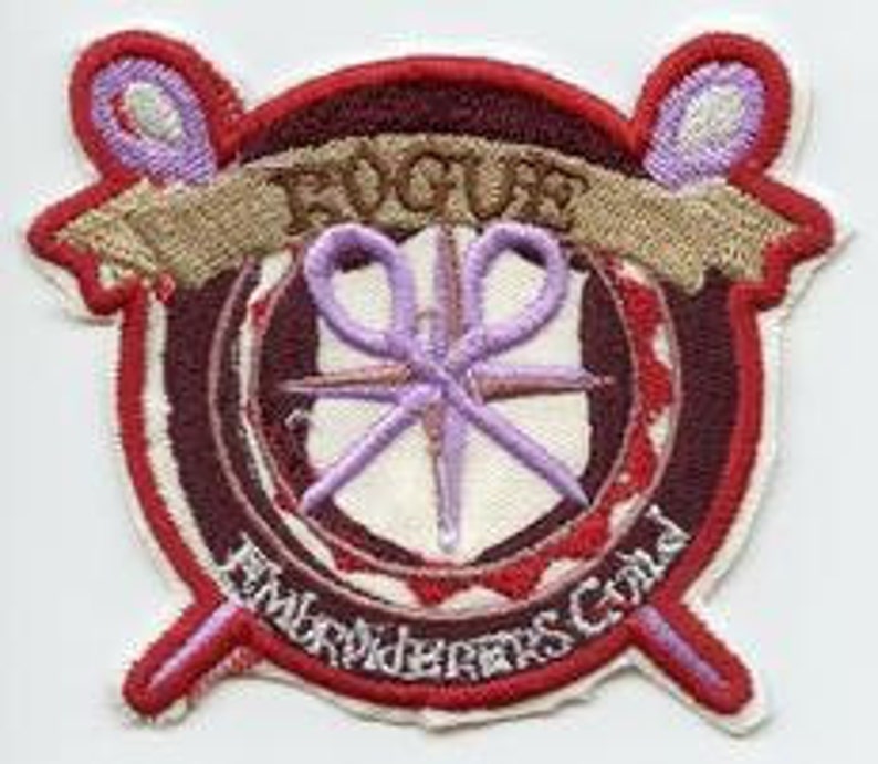 May include: A red, white and purple embroidered patch with the word "ROGUE" in a banner above a pair of scissors and the words "Embroiderers Guild" below.