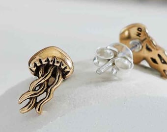 May include: A pair of gold-toned stud earrings featuring a detailed jellyfish design. The earrings have a post and butterfly backing.