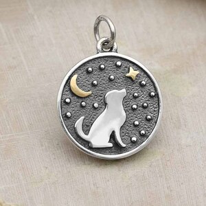 May include: Silver charm with a dog silhouette looking up at a crescent moon and star against a dark background with white dots.