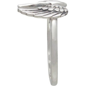 May include: A silver ring featuring a detailed wing design. The wing is positioned at the top of the ring, with the band extending downwards. The ring is made of a shiny, metallic material.