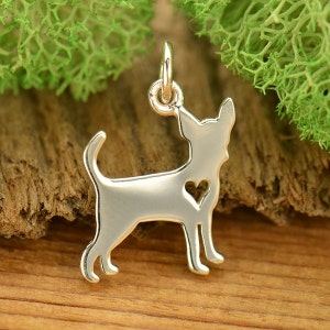 May include: Silver charm in the shape of a Chihuahua with a heart cut out of its chest. The charm is hanging from a silver jump ring.