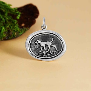 May include: Silver pendant featuring a detailed, black and white illustration of a dog running through tall grass.