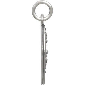 May include: A silver charm in the shape of a half moon with a beaded edge. The charm has a loop at the top for attaching to a bracelet or necklace.