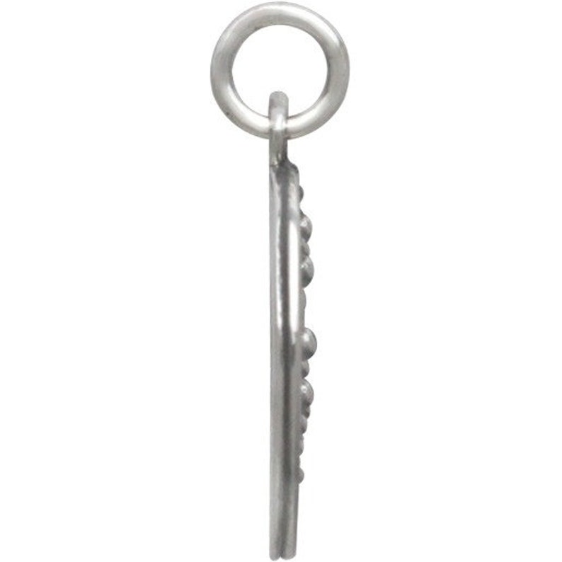 May include: A silver charm in the shape of a half moon with a beaded edge. The charm has a loop at the top for attaching to a bracelet or necklace.