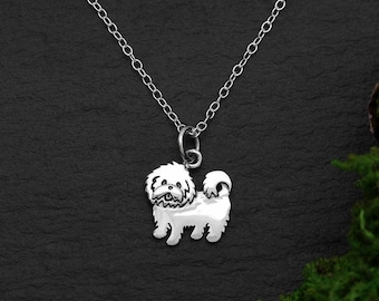 May include: A silver necklace with a small, detailed charm of a white Shih Tzu dog.