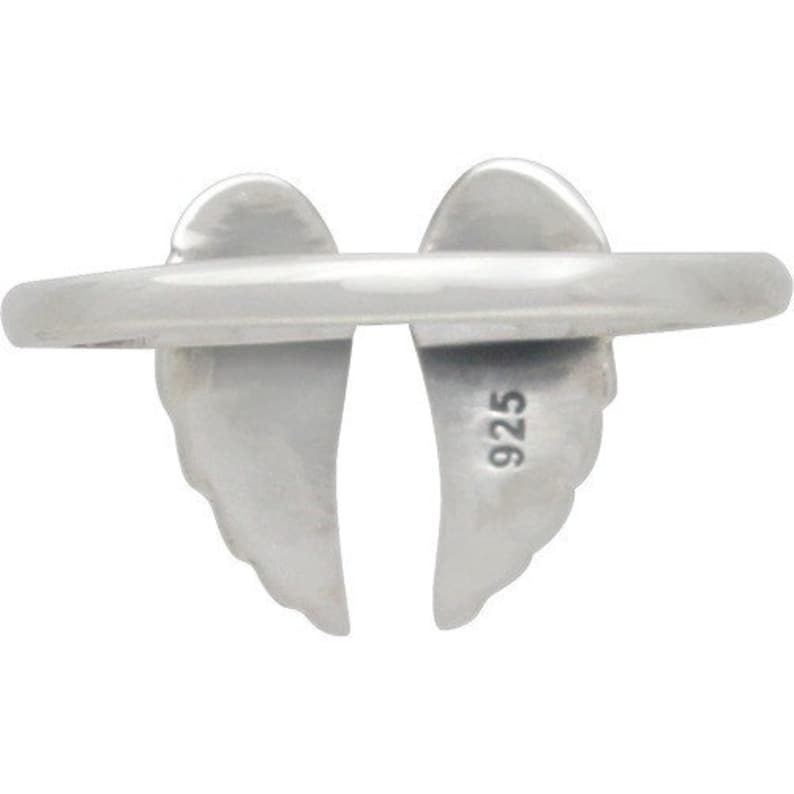 May include: A silver ring featuring a pair of stylized angel wings. The ring's band is smooth and connects the wings, which are detailed with feather-like textures. The number "925" is stamped on one of the wings, indicating the metal's purity.