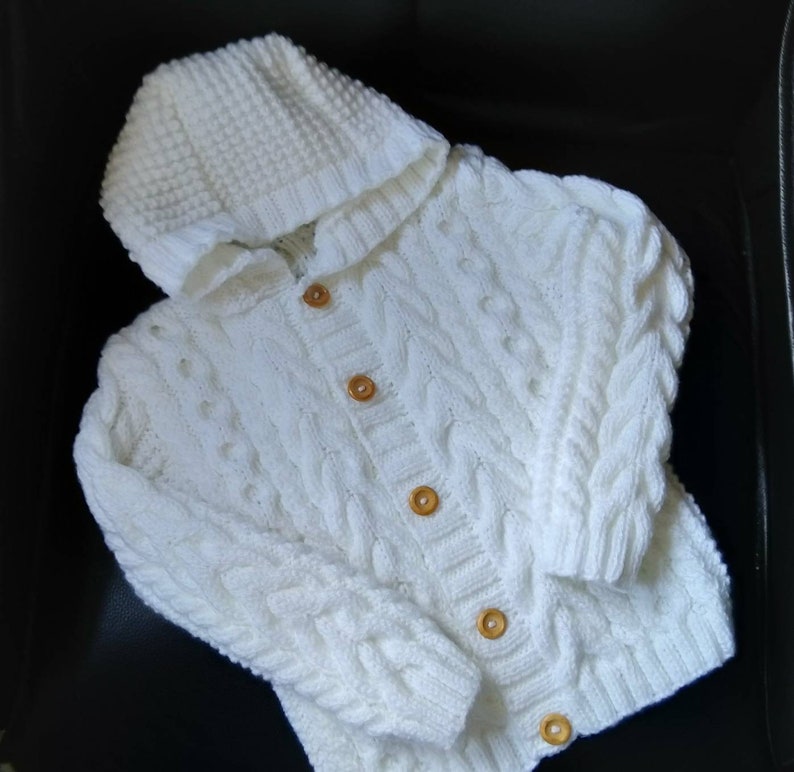 hand knitted childrens aran hoodie. Cable pattern to body and sleeves. Round wooden buttons. machine washable. Various sizes and colours possible