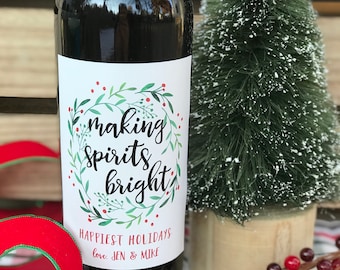 May include: A wine bottle with a white label that says "making spirits bright." The label also has a green wreath with red berries and the text "Happiest Holidays love. JEN & MIKE".