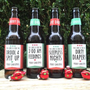May include: Four brown beer bottles with green and red labels. The labels have text that reads "This one is for the Drool & Spit Up", "This one is for the 3:00 AM Feedings", "This one is for the Sleepless Nights", and "This one is for the Dirty Diapers". Each label has the text "Merry Christmas" at the bottom.