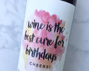 Puede incluir: Una botella de vino con una etiqueta blanca que presenta un diseño de acuarela en tonos de rosa, naranja y amarillo. La etiqueta dice "wine is the best cure for birthdays CHEERS!" y "BIRTHDAY BLEND | VINTAGE 1961".