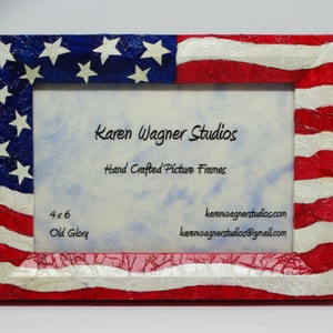 May include: Rectangular picture frame with a patriotic American flag design. The frame features red and white stripes, a blue field with white stars, and the text "Karen Wagner Studios". The frame is 4x6 inches.