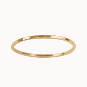 May include: A simple gold band ring.
