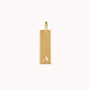 May include: Gold charm with the letter A engraved on a rectangular tag.